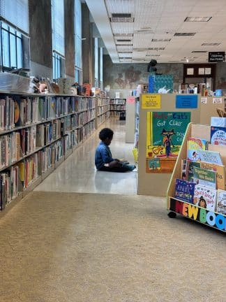 Son sitting on library floor looking at picture books pointing out pictures that interest him. 