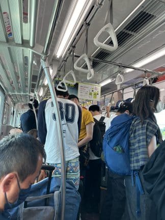 Inside a Japanese train with passengers waiting for their next stop. 