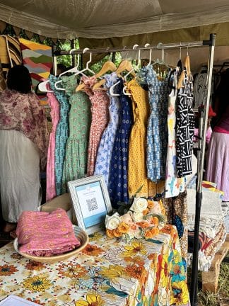 Pockets of orange set up at market. Beautiful bright colored African print dresses in display .