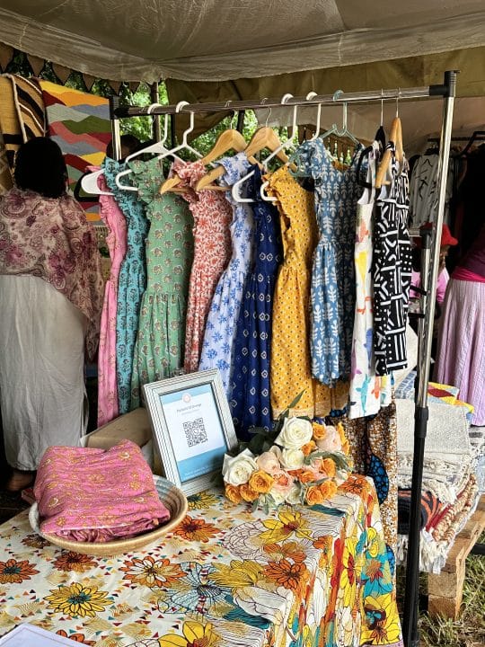 Pockets of orange set up at market. Beautiful bright colored African print dresses in display .