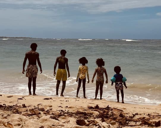 5 kids overlooking the edge of a blue gray lake